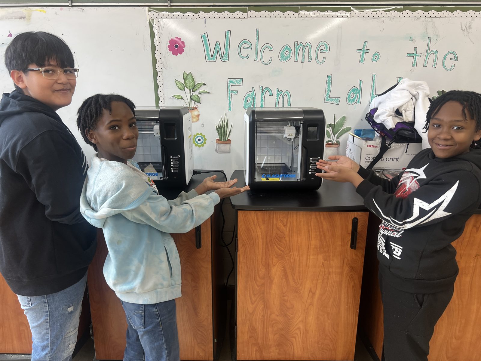 Three students of the Cosmic STEM Club present the 3D printers they learned with AI